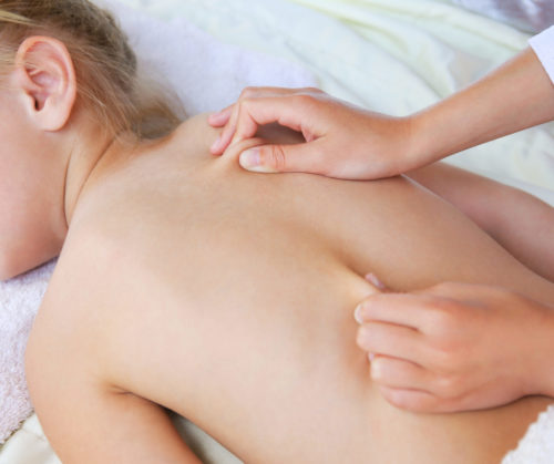 Masseur doing back massage to child.